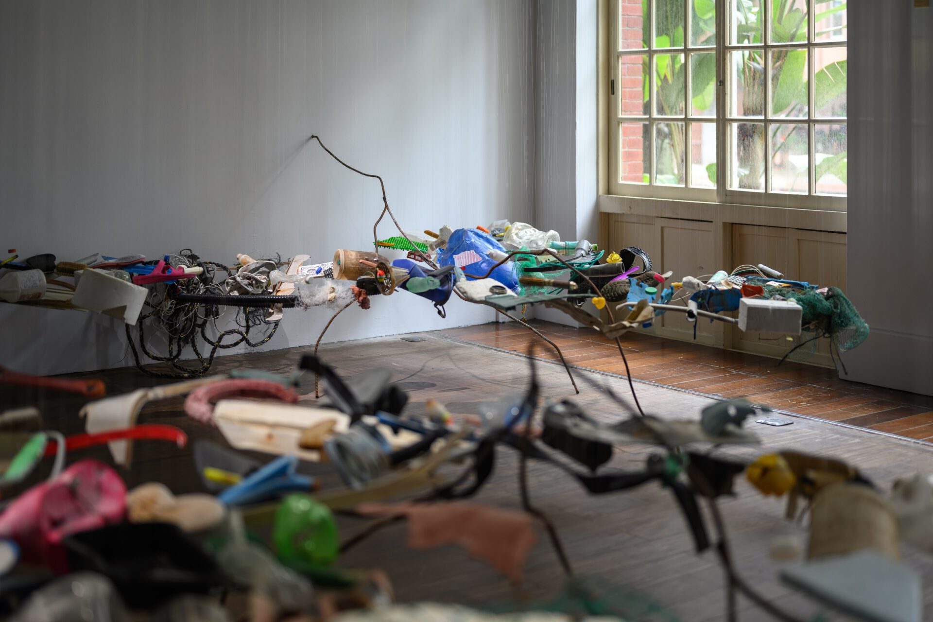 Side view of the suspended assemblage beside a large gallery window.