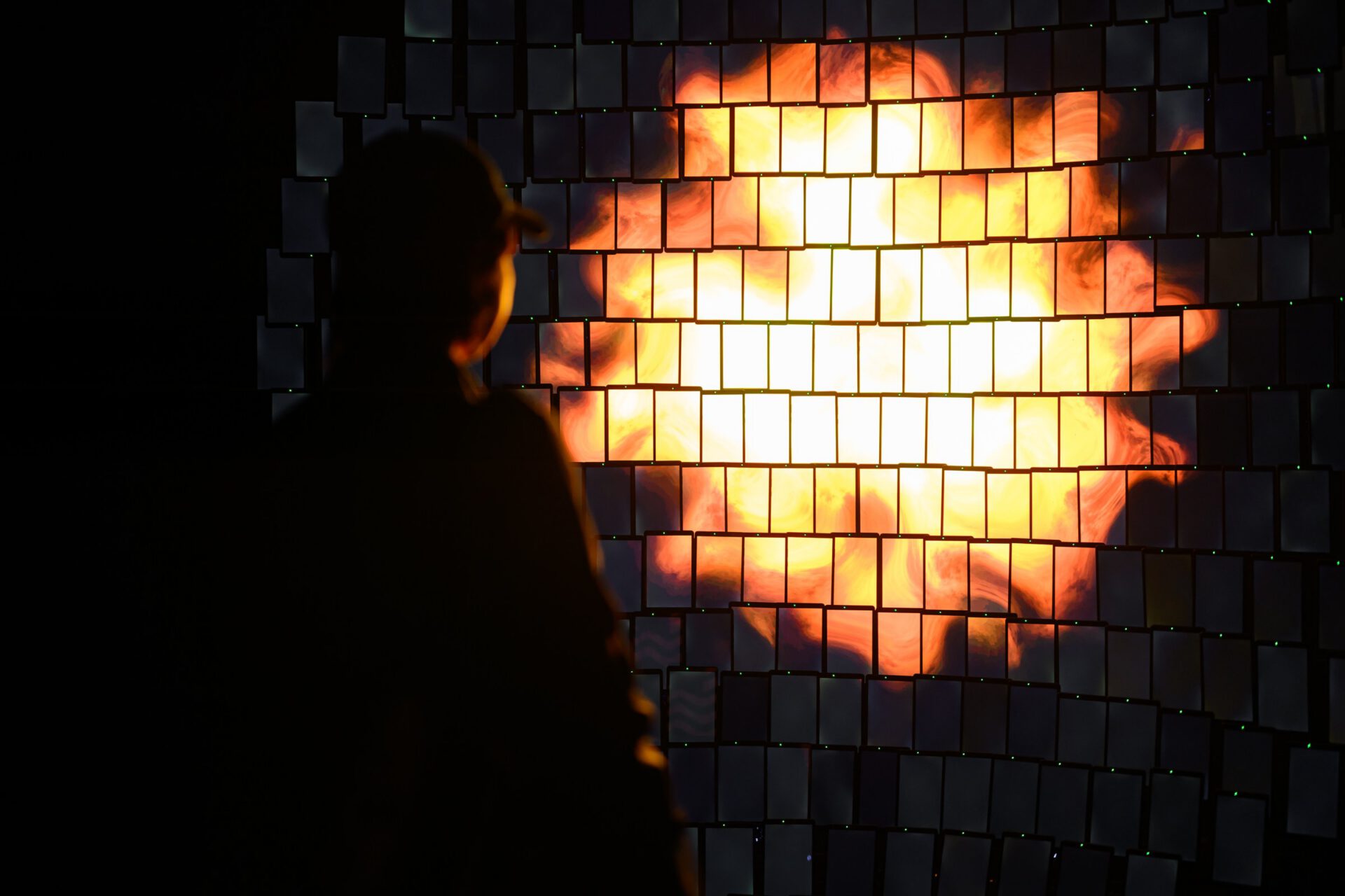 Visitor silhouetted in front of the illuminated circular screen installation.