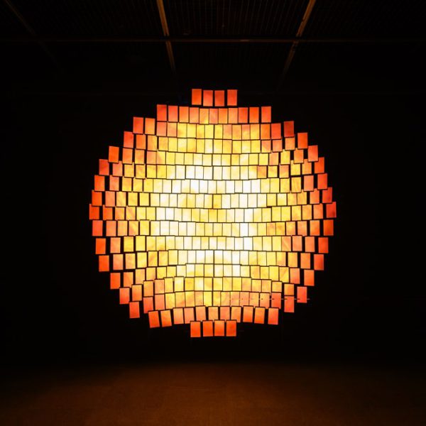 Glowing circular arrangement of illuminated rectangular screens in a dark room.
