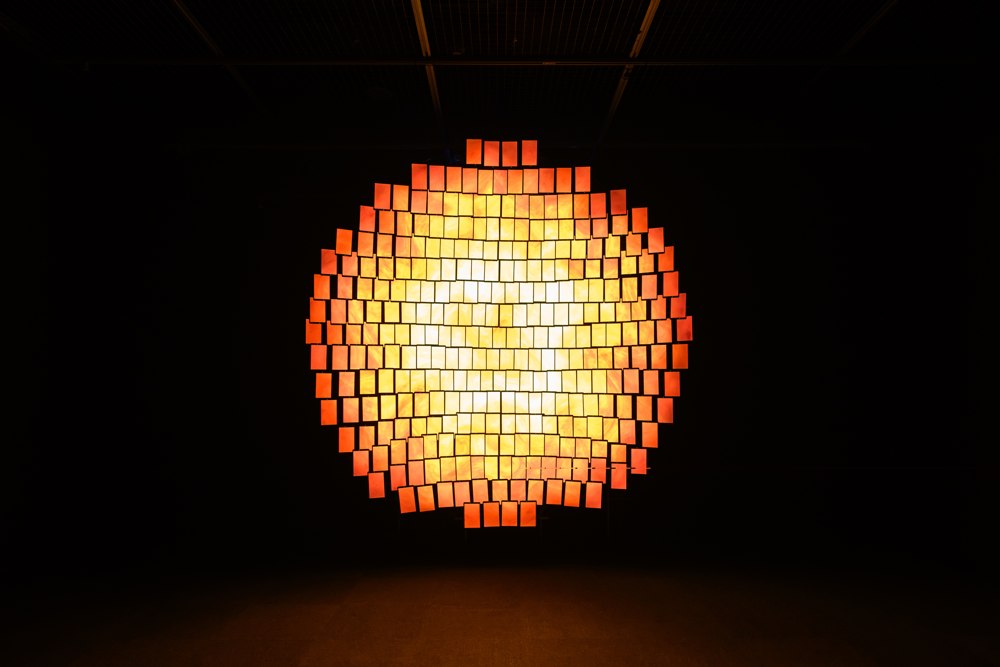 Glowing circular arrangement of illuminated rectangular screens in a dark room.